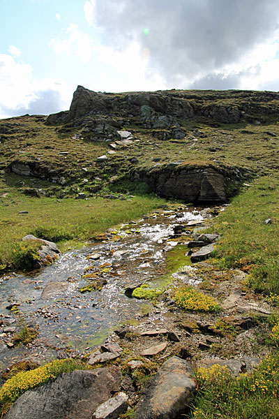 Der Bach entspringt unterhalb eines Felsens