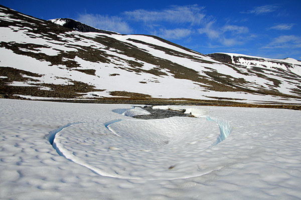 Schneefeld mit Wasserlauf
